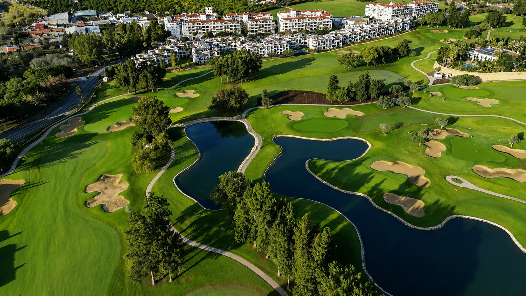 Aerial view of a Spanish resort golf course with lakes and palm avenues