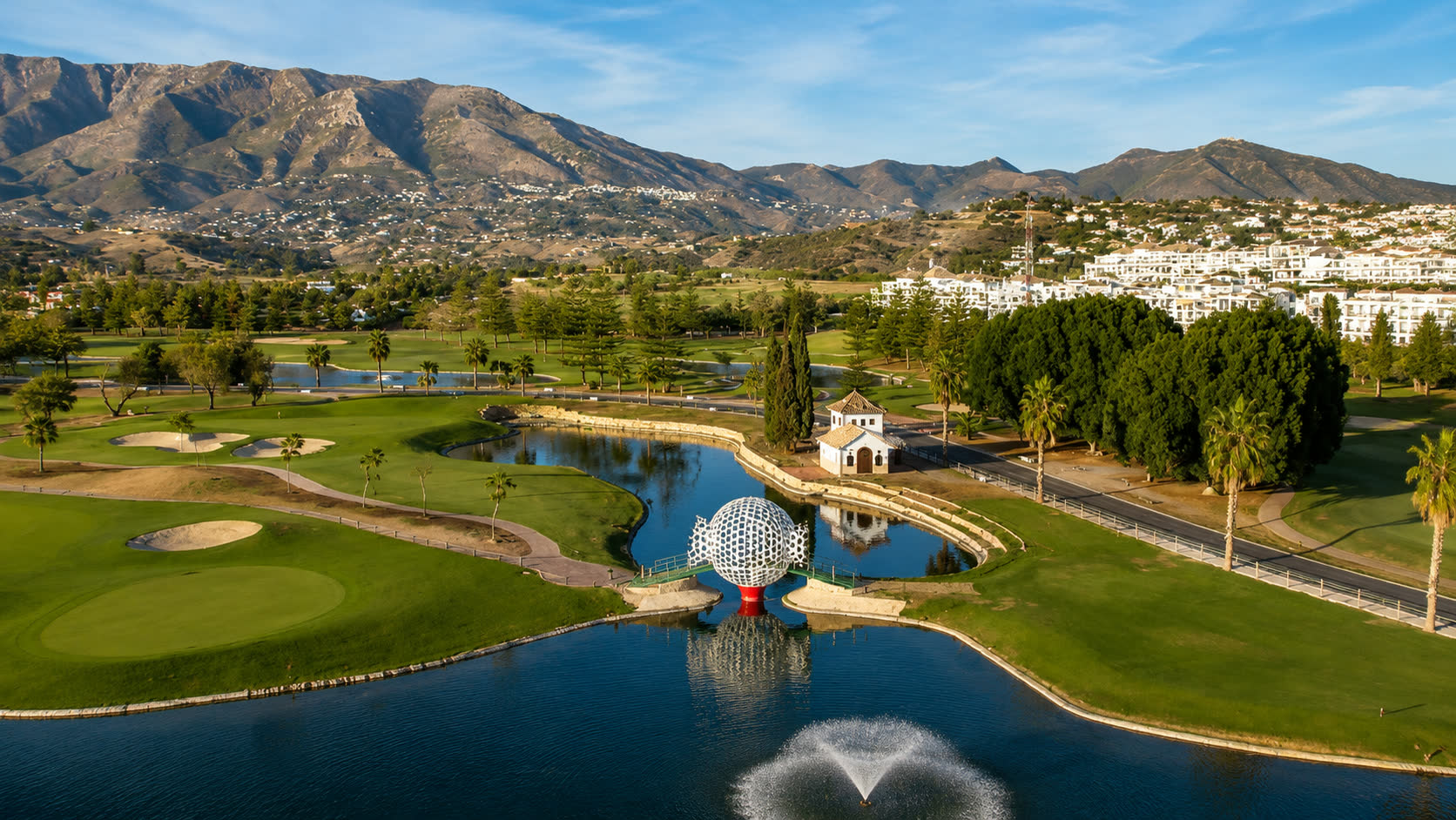 Resort golf course with lakes below a mountain ridge